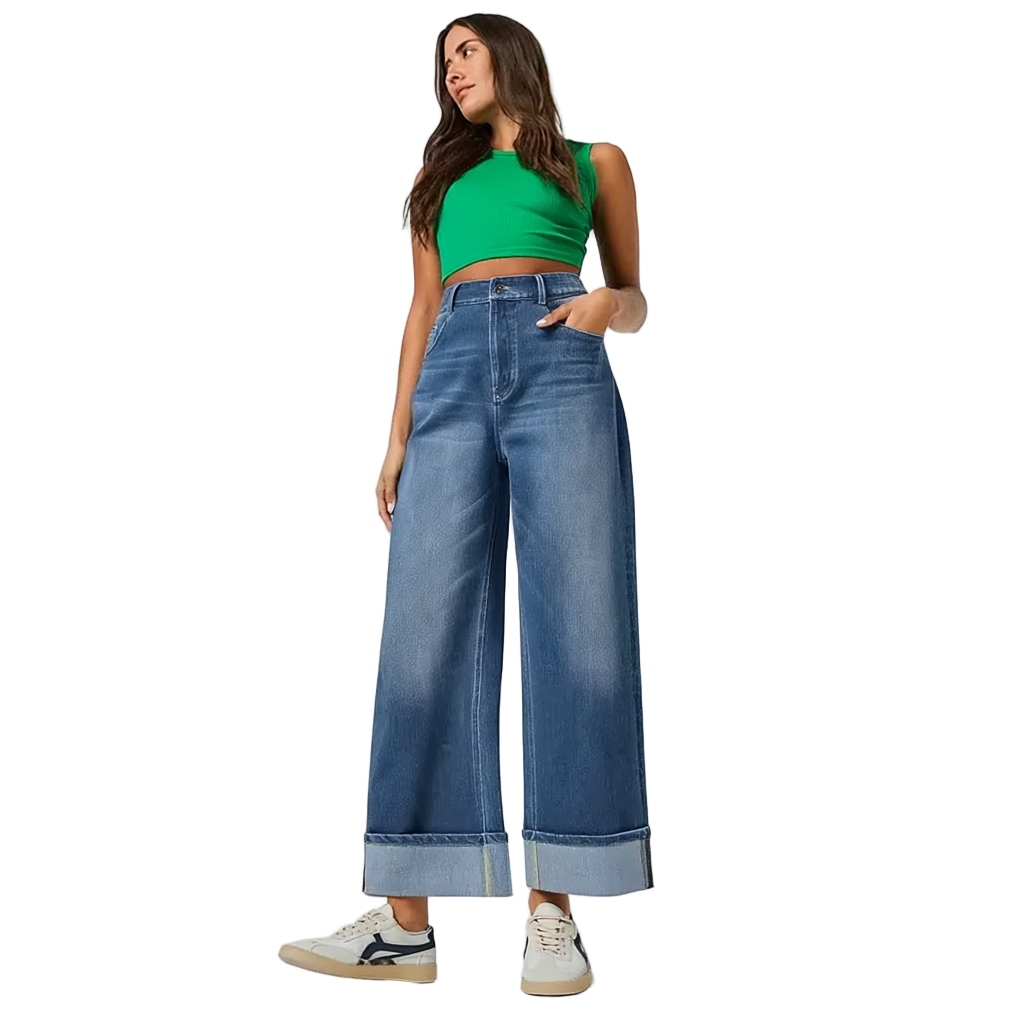 Woman wearing a green crop top and blue wide-leg jeans on a white background